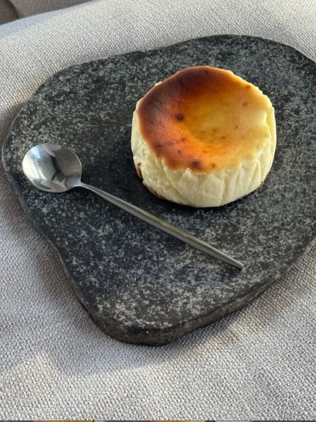 A whole Classic tartza with its burnt golden top on a dark stone slab